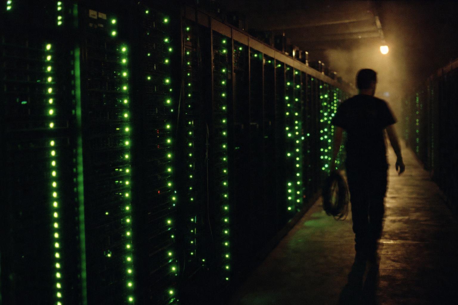 A wall of server racks glowing green in a dark room