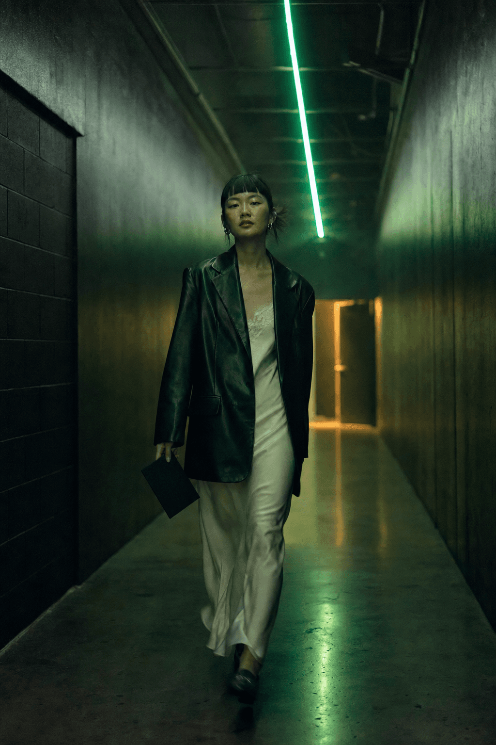 A member walking a neon-lined corridor toward the club door, card in hand
