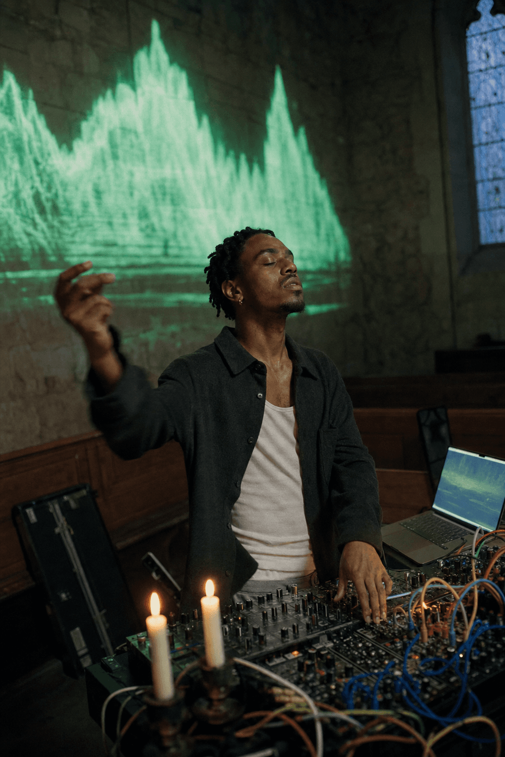 A musician conducting a projected waveform landscape at night