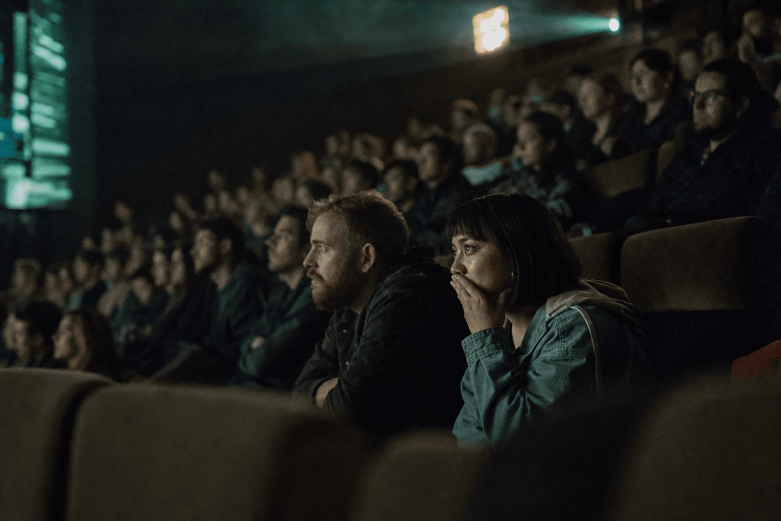An audience uplit emerald by the screen they are watching